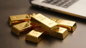 Gold bars on table with laptop in background