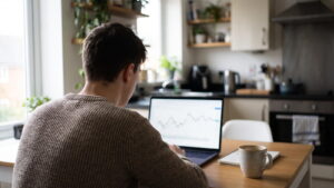 Trader practising on a laptop at a kitchen table with a cup of tea